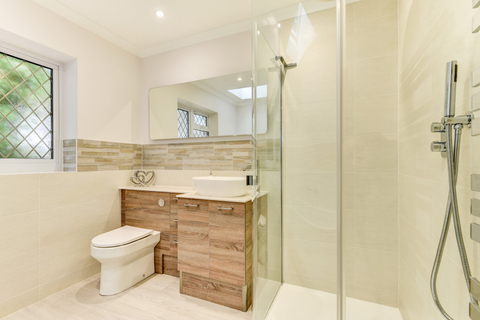 Medium sized modern bathroom in Sussex with flat-panel cabinets, medium wood cabinets, a built-in bath, a walk-in shower, a wall mounted toilet, beige tiles, ceramic tiles, white walls, light hardwood flooring, a console sink, quartz worktops, brown floors, an open shower, white worktops, feature lighting, a single sink and a built in vanity unit.