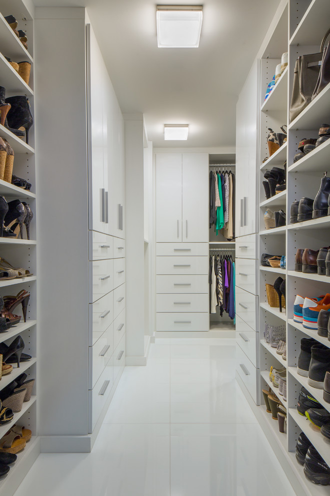 Photo of a large contemporary gender-neutral walk-in wardrobe in New York with flat-panel cabinets, white cabinets, white floor and marble floors.