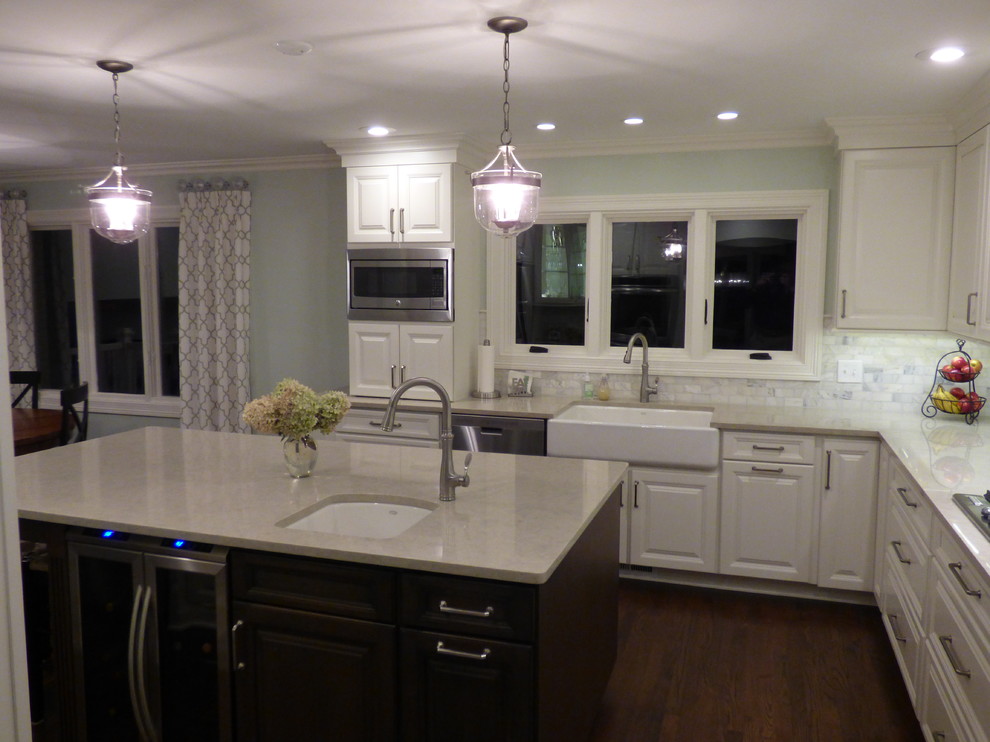 Inspiration for a large transitional u-shaped dark wood floor eat-in kitchen remodel in Chicago with a farmhouse sink, raised-panel cabinets, white cabinets, quartz countertops, gray backsplash, stone tile backsplash, stainless steel appliances and an island