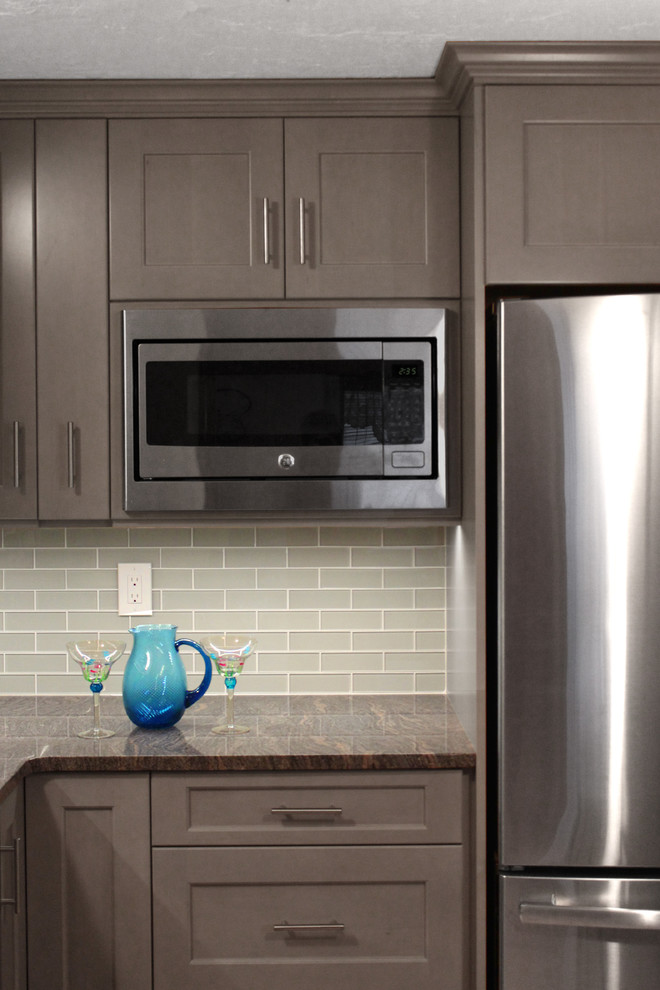Inspiration for a mid-sized transitional l-shaped ceramic tile eat-in kitchen remodel in Boston with an undermount sink, shaker cabinets, gray cabinets, granite countertops, gray backsplash, glass tile backsplash, stainless steel appliances and an island