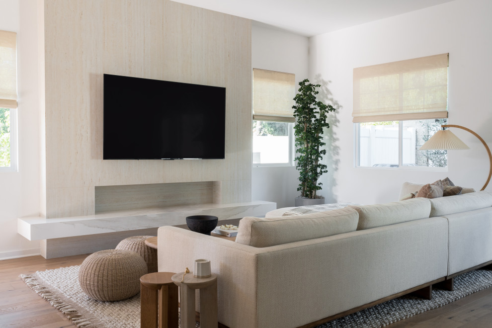 Modelo de salón abierto nórdico de tamaño medio con paredes blancas, suelo de madera clara, televisor colgado en la pared y suelo beige