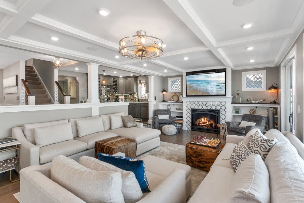 Inspiration for a large contemporary open concept living room in Milwaukee with a home bar, grey walls, light hardwood floors, a standard fireplace, a tile fireplace surround, a wall-mounted tv, beige floor and coffered.