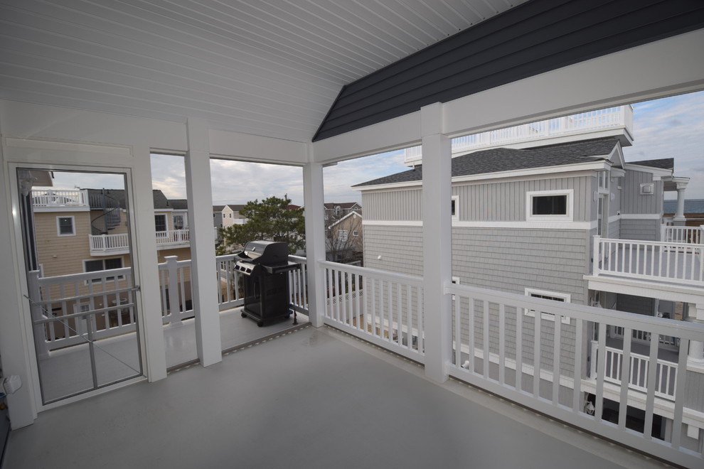 Photo of a beach style side yard screened-in verandah in New York with a roof extension.