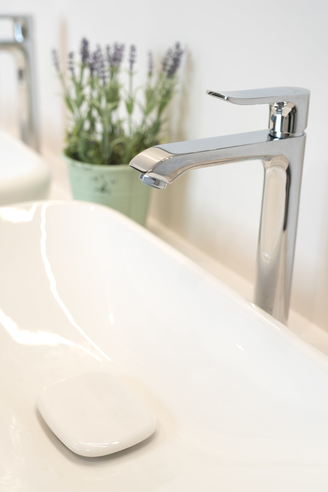 Idée de décoration pour une salle de bain design avec un bain bouillonnant, WC suspendus, un carrelage blanc, des carreaux de céramique, un sol en vinyl, une grande vasque, un plan de toilette en quartz et un sol gris.