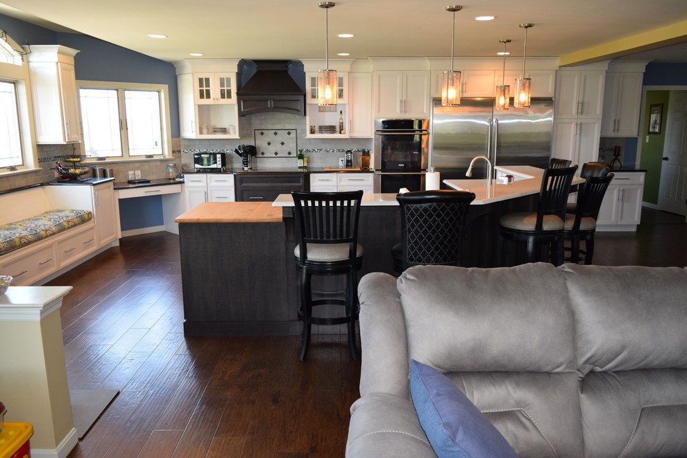 Inspiration for a transitional medium tone wood floor kitchen remodel with an undermount sink, white cabinets, quartz countertops, gray backsplash, ceramic backsplash, stainless steel appliances and recessed-panel cabinets