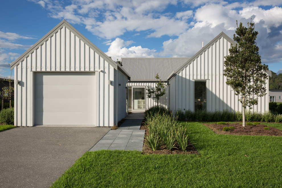 Inspiration for a mid-sized industrial one-storey white house exterior in Auckland with metal siding, a gable roof and a metal roof.