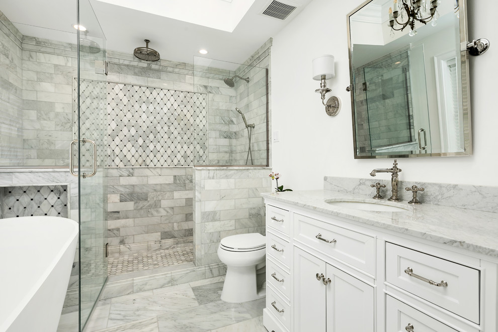 Photo of a mid-sized traditional bathroom in St Louis with beaded inset cabinets, white cabinets, a freestanding tub, gray tile, marble, white walls, an undermount sink, grey floor and grey benchtops.
