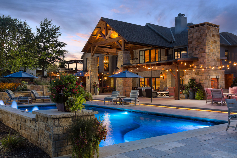 Expansive country backyard rectangular lap pool in Kansas City with a water feature and natural stone pavers.