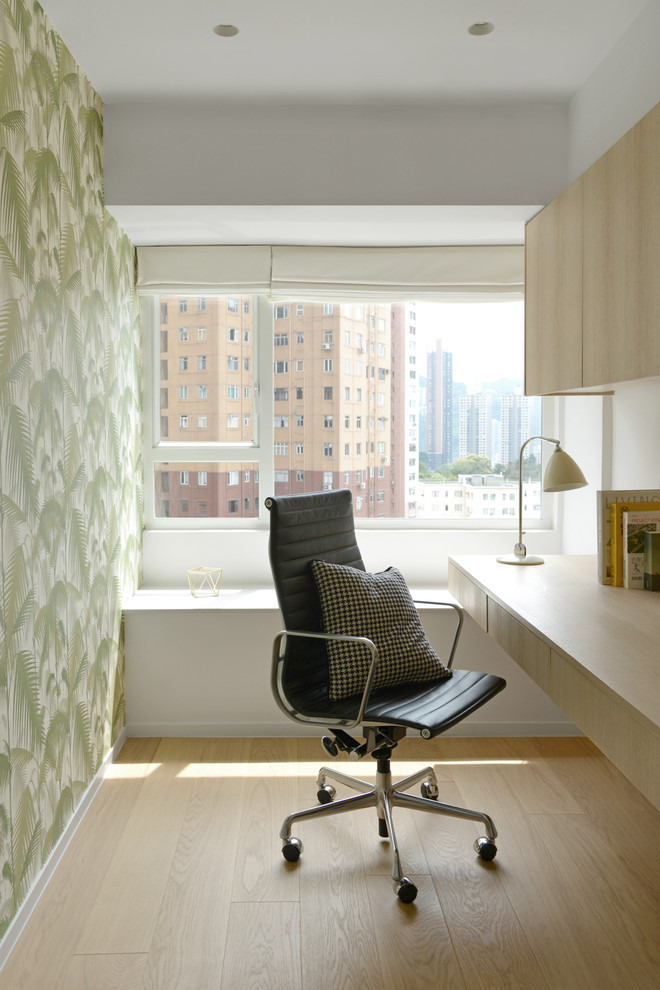 Scandinavian study room in Hong Kong with green walls, light hardwood floors and a built-in desk.