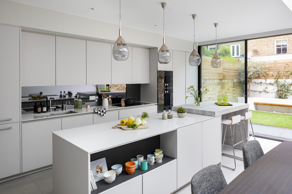 Design ideas for an expansive contemporary single-wall kitchen in London with flat-panel cabinets, grey cabinets, wood benchtops, grey splashback, mirror splashback, panelled appliances, ceramic floors, with island, grey floor, grey benchtop and an undermount sink.