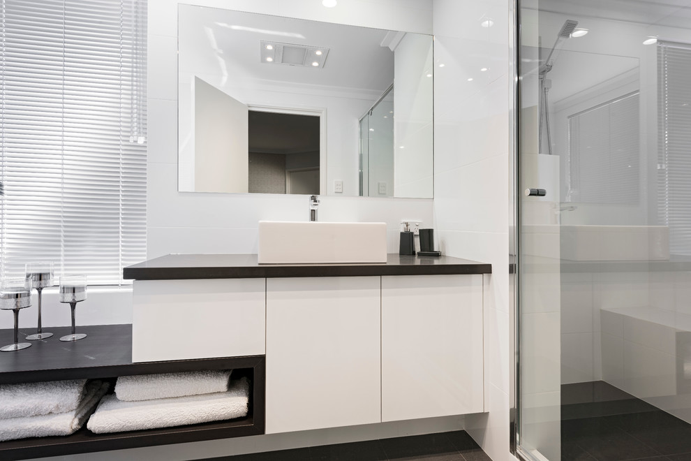 Inspiration for a mid-sized contemporary 3/4 bathroom in Perth with recessed-panel cabinets, white cabinets, white tile, ceramic tile, white walls, porcelain floors, a vessel sink, engineered quartz benchtops, an alcove shower and a one-piece toilet.