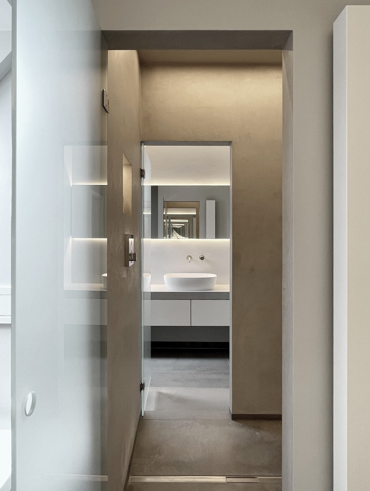 Mid-sized contemporary 3/4 wet room bathroom in Dusseldorf with flat-panel cabinets, white cabinets, a wall-mount toilet, gray tile, grey walls, ceramic floors, a vessel sink, grey floor, a hinged shower door, grey benchtops, a single vanity and a freestanding vanity.