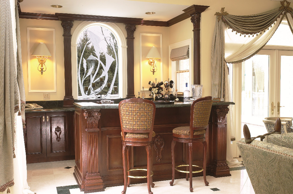 This is an example of a mid-sized traditional u-shaped seated home bar in New York with an undermount sink, recessed-panel cabinets, dark wood cabinets, marble benchtops and marble floors.