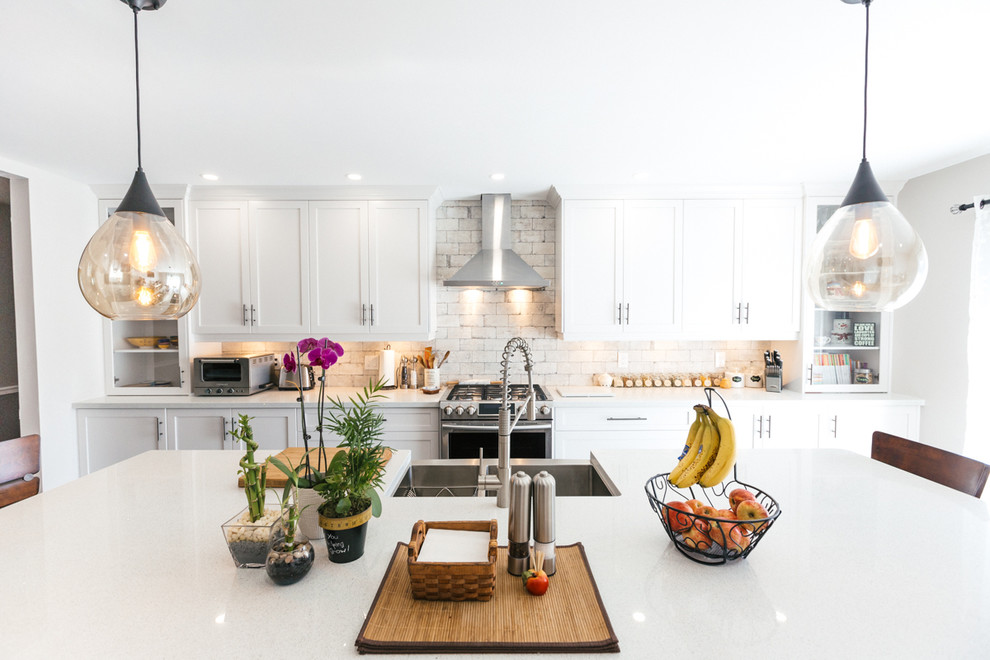 Example of a large transitional single-wall dark wood floor enclosed kitchen design in Toronto with a farmhouse sink, shaker cabinets, white cabinets, granite countertops, white backsplash, stone tile backsplash, stainless steel appliances and an island