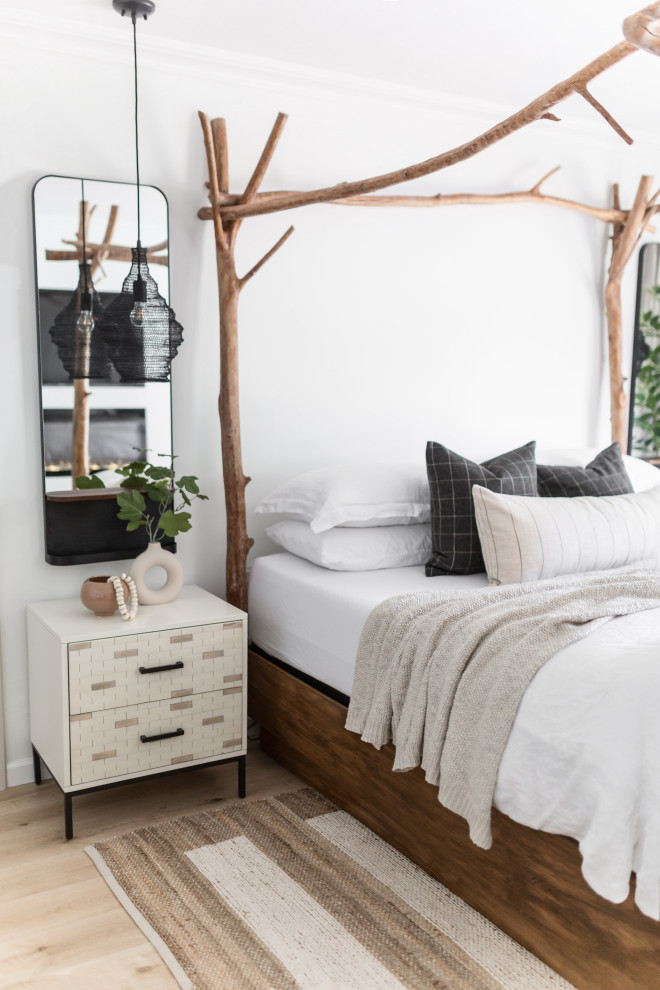 Mid-sized eclectic master bedroom in Phoenix with white walls, light hardwood floors, a ribbon fireplace and a plaster fireplace surround.