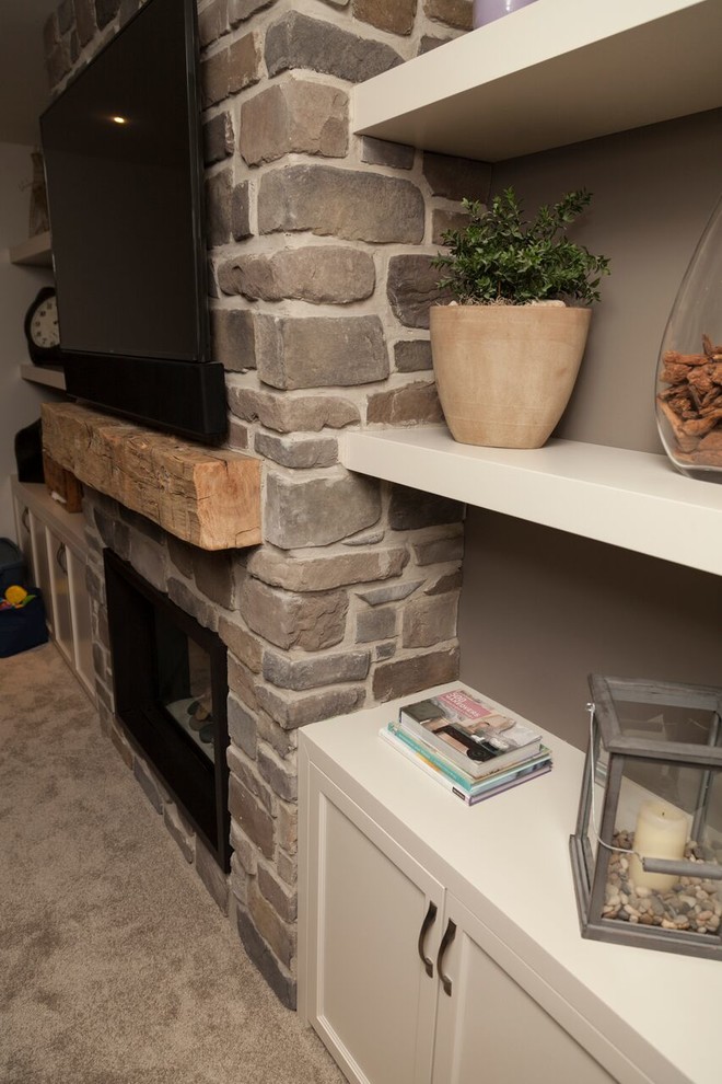 Basement - transitional carpeted basement idea in Toronto with gray walls, a standard fireplace and a stone fireplace