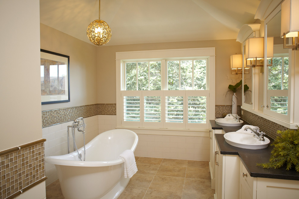 Large traditional master bathroom in Grand Rapids with a drop-in sink, shaker cabinets, white cabinets, a freestanding tub, beige tile, beige walls, travertine floors, a two-piece toilet, mosaic tile, soapstone benchtops and beige floor.
