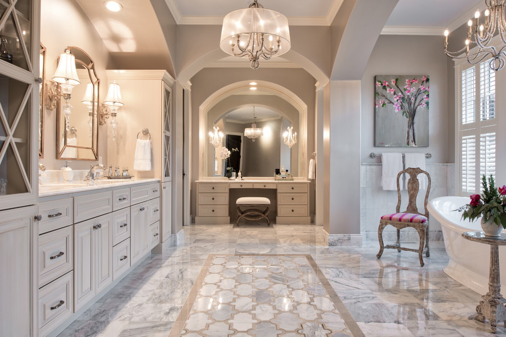 Photo of a traditional master bathroom in Minneapolis with raised-panel cabinets, beige cabinets, a freestanding tub, grey walls, an undermount sink, grey floor and white benchtops.