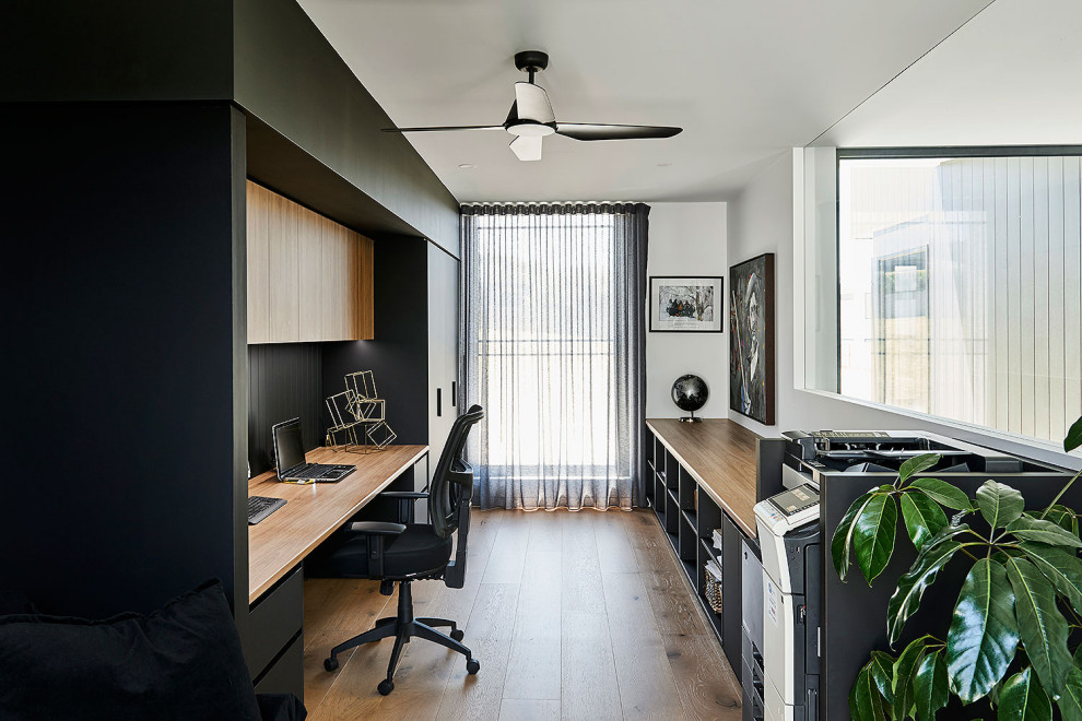 Foto de despacho actual grande con paredes blancas, suelo de madera en tonos medios, escritorio empotrado y suelo marrón
