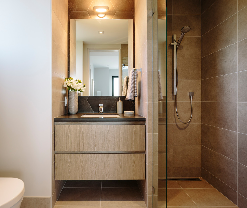 Inspiration for a large contemporary kids bathroom in Vancouver with flat-panel cabinets, medium wood cabinets, a curbless shower, a wall-mount toilet, porcelain tile, porcelain floors, engineered quartz benchtops, a hinged shower door, grey benchtops, brown tile, white walls, an undermount sink and brown floor.