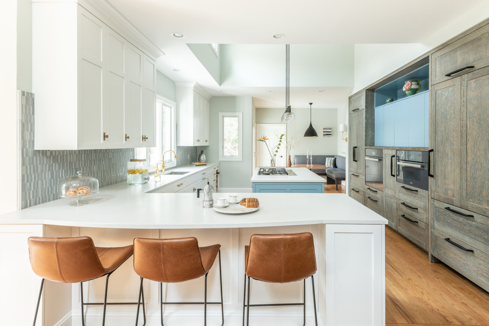 Example of a large transitional l-shaped kitchen pantry design in DC Metro with shaker cabinets, blue cabinets, wood countertops, blue backsplash, ceramic backsplash, paneled appliances and an island
