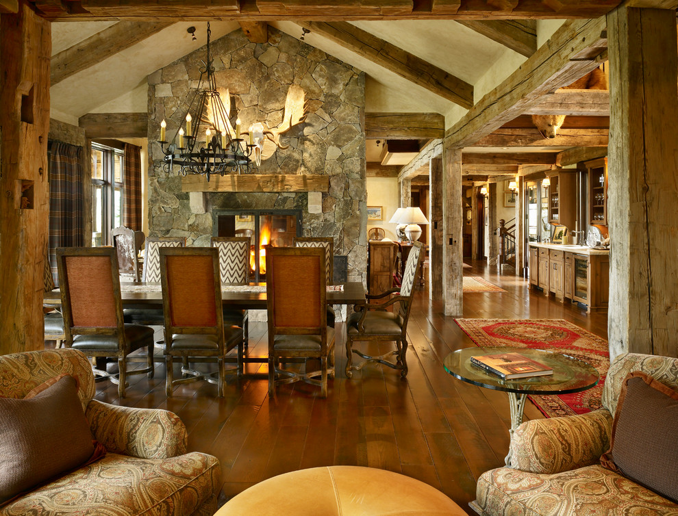 Country open plan dining in Denver with beige walls, dark hardwood floors, a two-sided fireplace and a stone fireplace surround.
