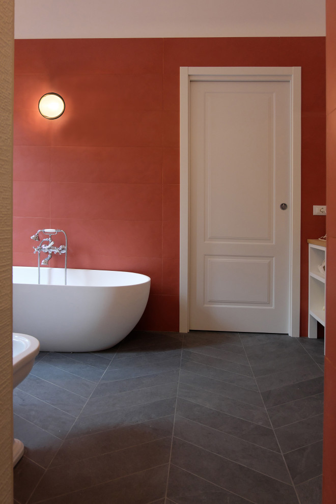 This is an example of a large scandinavian bathroom in Milan with furniture-like cabinets, white cabinets, a freestanding tub, a curbless shower, red tile, porcelain tile, white walls, porcelain floors, a vessel sink, wood benchtops, grey floor, brown benchtops, a single vanity and a built-in vanity.