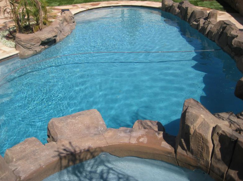 Hot tub - large rustic backyard stone and kidney-shaped natural hot tub idea in Los Angeles