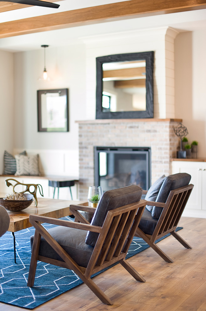 Inspiration for a mid-sized transitional open concept living room in Other with grey walls, laminate floors, a standard fireplace, a brick fireplace surround, a wall-mounted tv and brown floor.