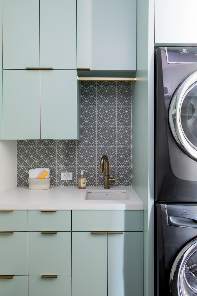 Design ideas for a large contemporary laundry room in San Francisco with an undermount sink, multi-coloured splashback, a stacked washer and dryer, white benchtop, flat-panel cabinets, turquoise cabinets, quartz benchtops, cement tile splashback, white walls, porcelain floors and black floor.