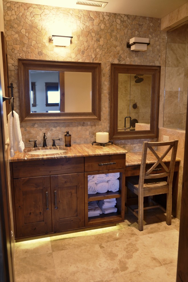 Inspiration for a mid-sized country 3/4 bathroom in Denver with an undermount sink, shaker cabinets, dark wood cabinets, an alcove shower, beige tile, pebble tile, beige walls, travertine floors, quartzite benchtops, beige floor and a hinged shower door.