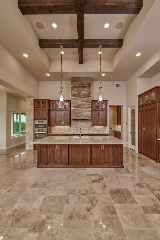Mid-sized transitional eat-in kitchen in Austin with an undermount sink, recessed-panel cabinets, brown cabinets, wood benchtops, beige splashback, marble splashback, stainless steel appliances, marble floors, with island, beige floor and beige benchtop.