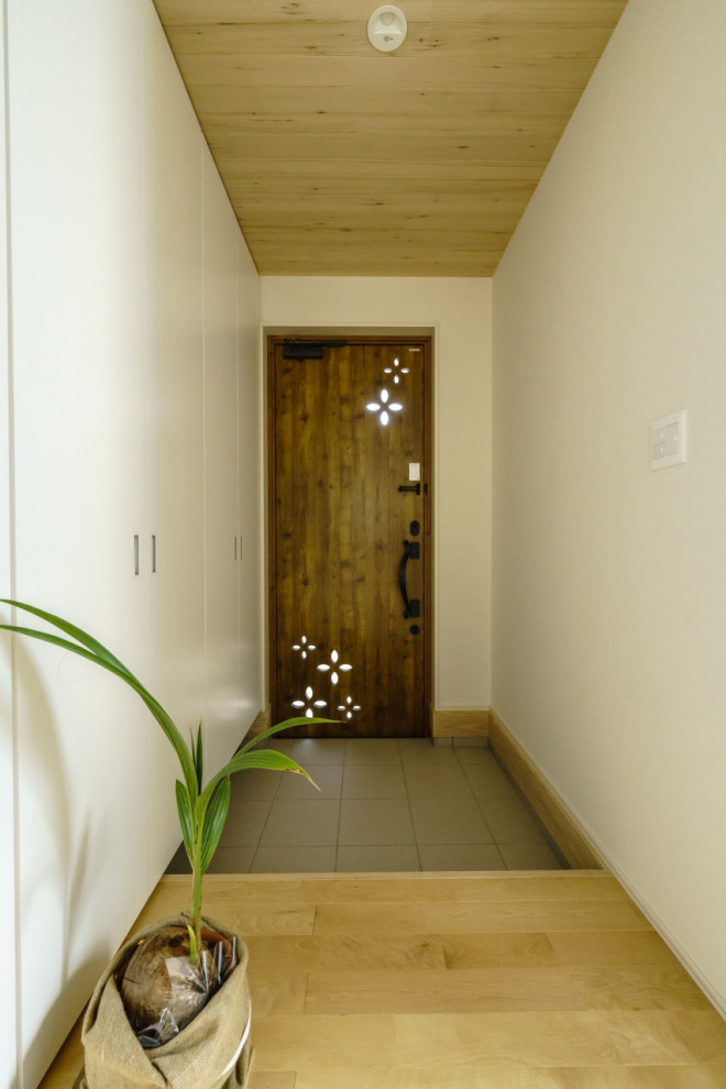 Foto di un ingresso o corridoio moderno di medie dimensioni con pareti bianche, parquet chiaro, una porta singola, una porta marrone, pavimento marrone, soffitto in carta da parati, carta da parati e armadio