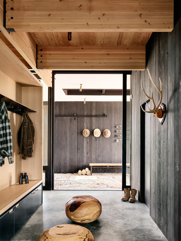 Inspiration for a mid-sized country mudroom in Austin with black walls and concrete floors.