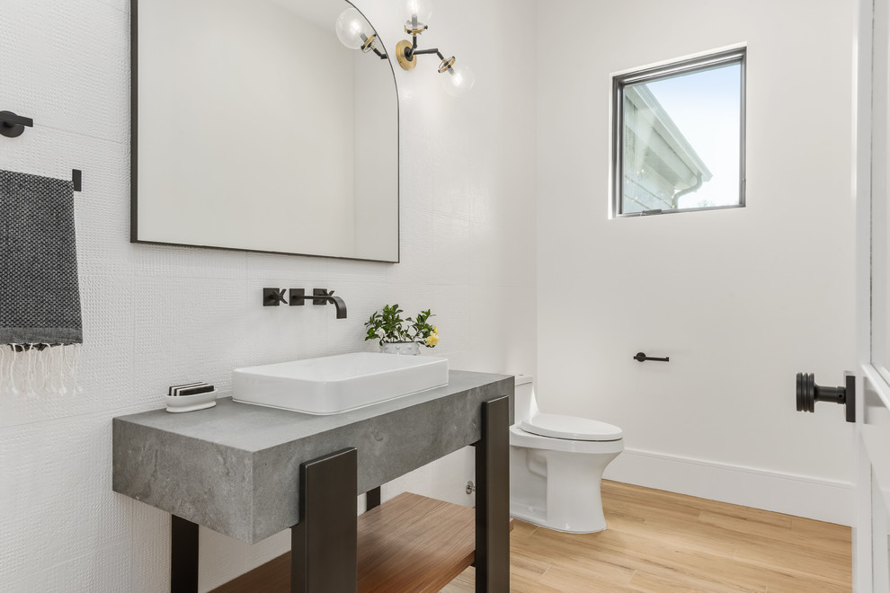 This is an example of a large contemporary powder room in Salt Lake City with open cabinets, a one-piece toilet, white tile, porcelain tile, white walls, porcelain floors, quartzite benchtops, grey benchtops, a vessel sink and brown floor.