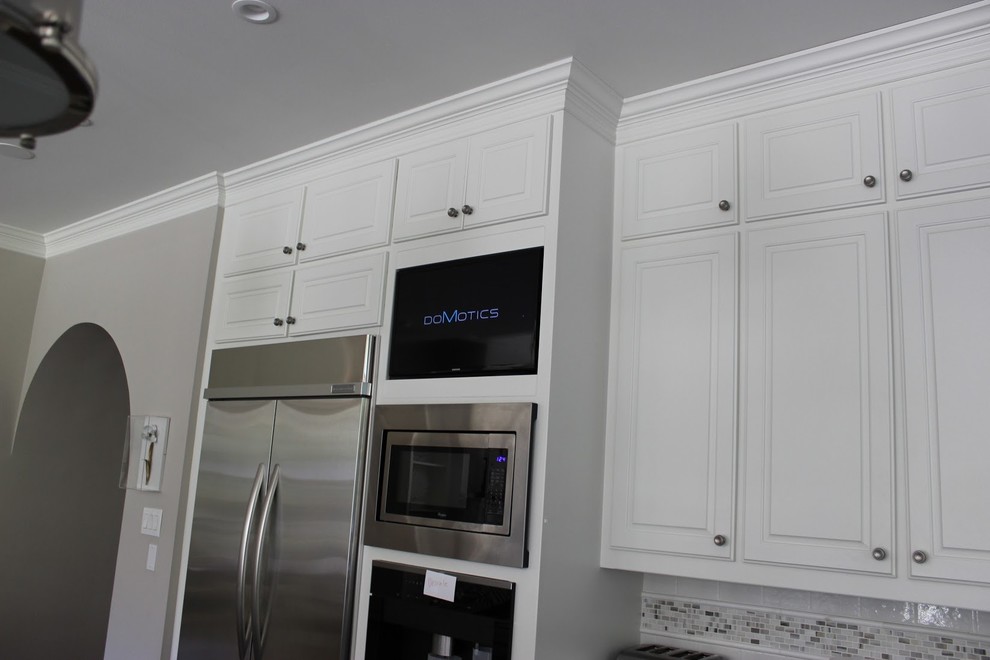 Photo of a contemporary kitchen in Dallas with raised-panel cabinets, white cabinets, multi-coloured splashback, mosaic tile splashback and stainless steel appliances.
