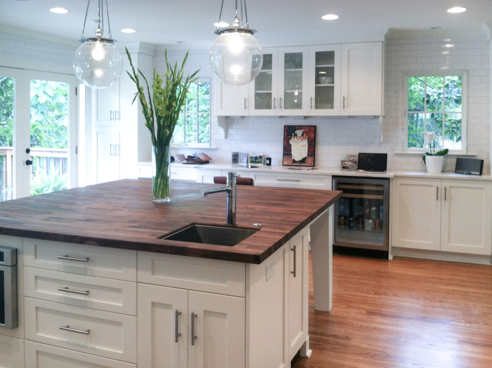 Large transitional u-shaped dark wood floor and brown floor eat-in kitchen photo in Atlanta with an undermount sink, recessed-panel cabinets, white cabinets, wood countertops, white backsplash, subway tile backsplash, stainless steel appliances, an island and brown countertops