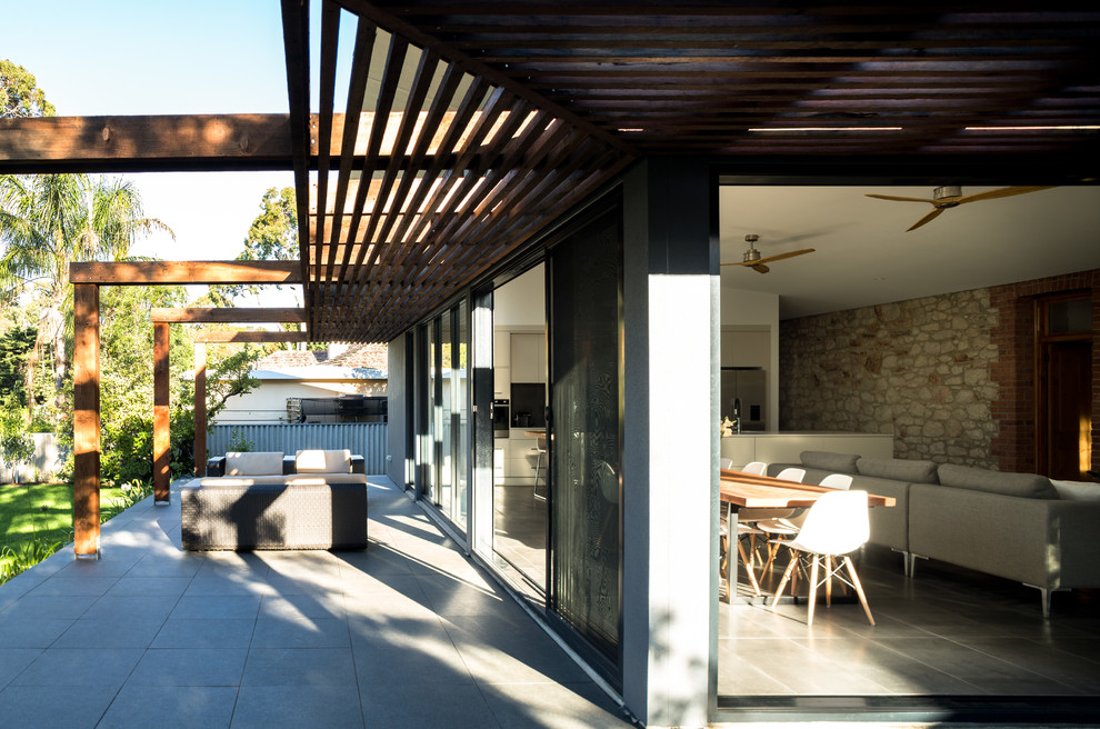 Photo of a large contemporary backyard verandah in Adelaide with tile and a pergola.