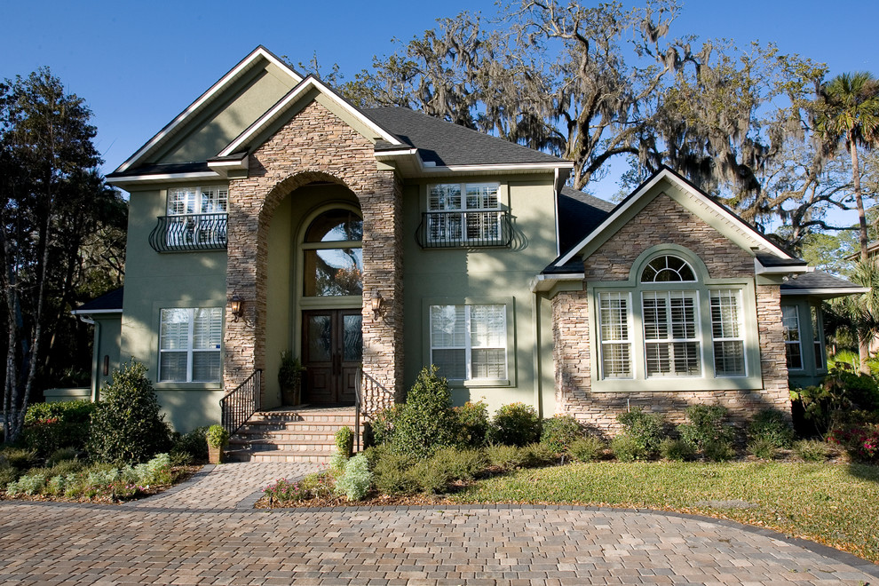 Inspiration for a large traditional two-storey green house exterior in Jacksonville with stone veneer and a shingle roof.