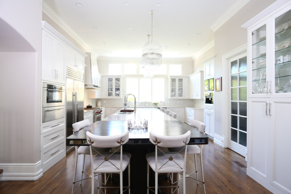 Inspiration for a huge transitional medium tone wood floor and brown floor open concept kitchen remodel with an undermount sink, recessed-panel cabinets, white cabinets, quartzite countertops, white backsplash, ceramic backsplash, stainless steel appliances, an island and white countertops