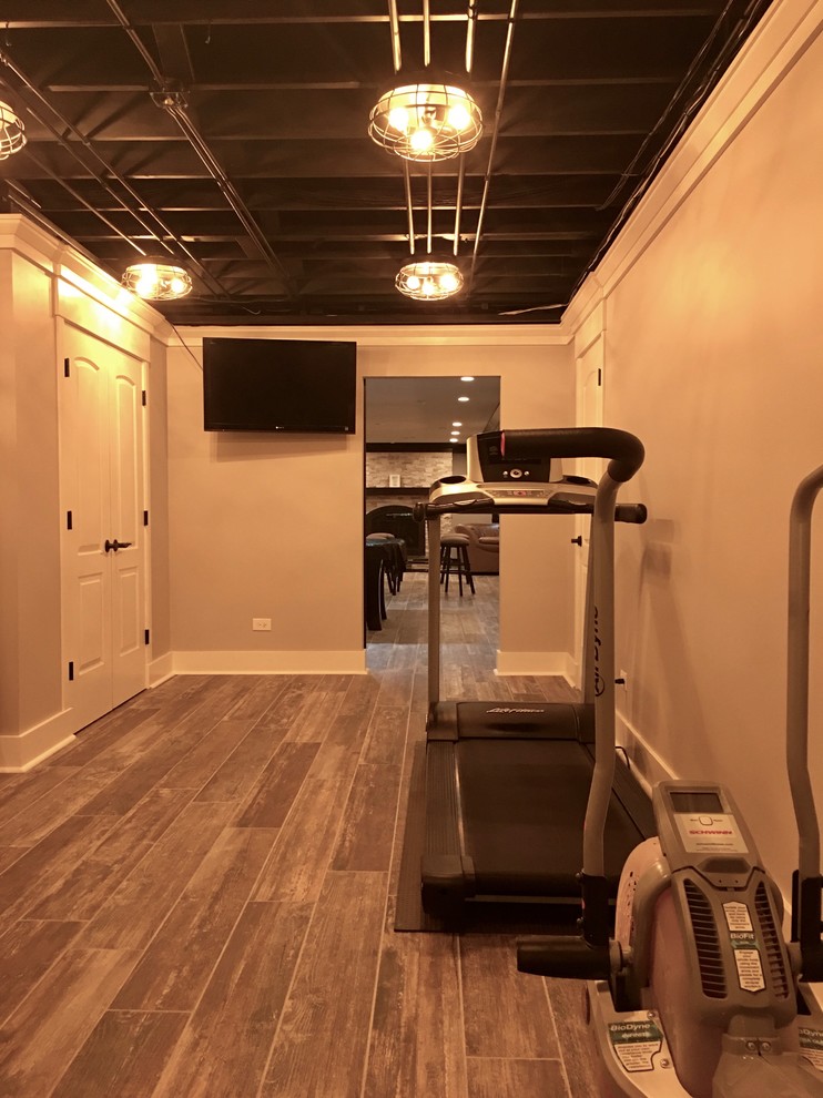 This is an example of a mid-sized transitional fully buried basement in Chicago with beige walls, dark hardwood floors, no fireplace and brown floor.