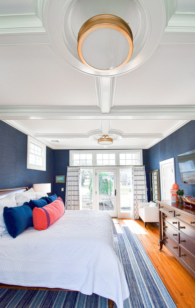 Large nautical master bedroom in Portland Maine with blue walls, medium hardwood flooring, a coffered ceiling and wood walls.