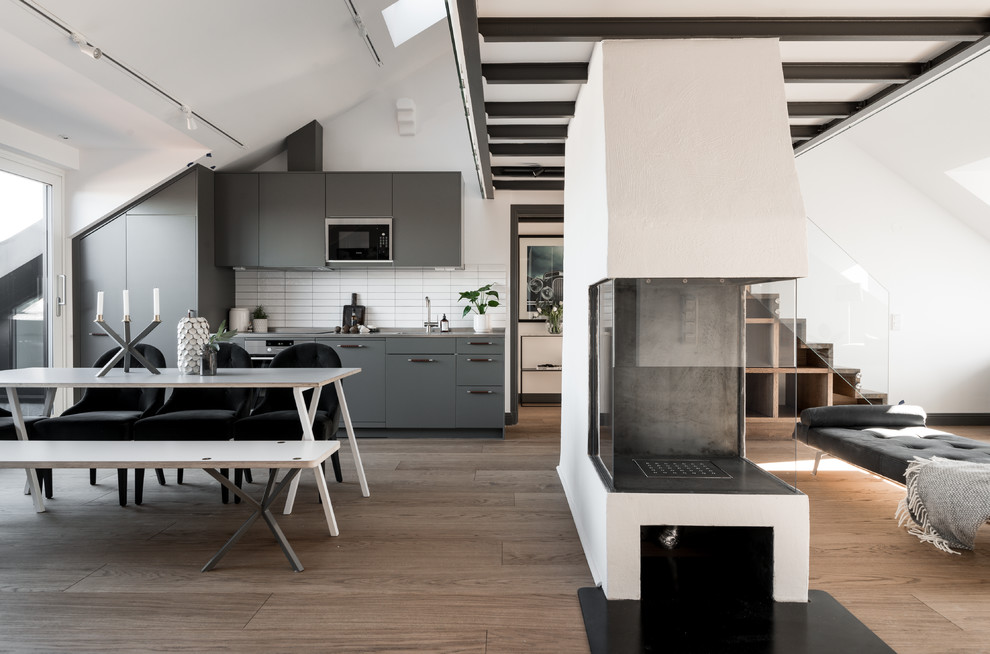 Photo of a scandinavian single-wall open plan kitchen in Stockholm with flat-panel cabinets, grey cabinets, white splashback, panelled appliances, brown floor and grey benchtop.