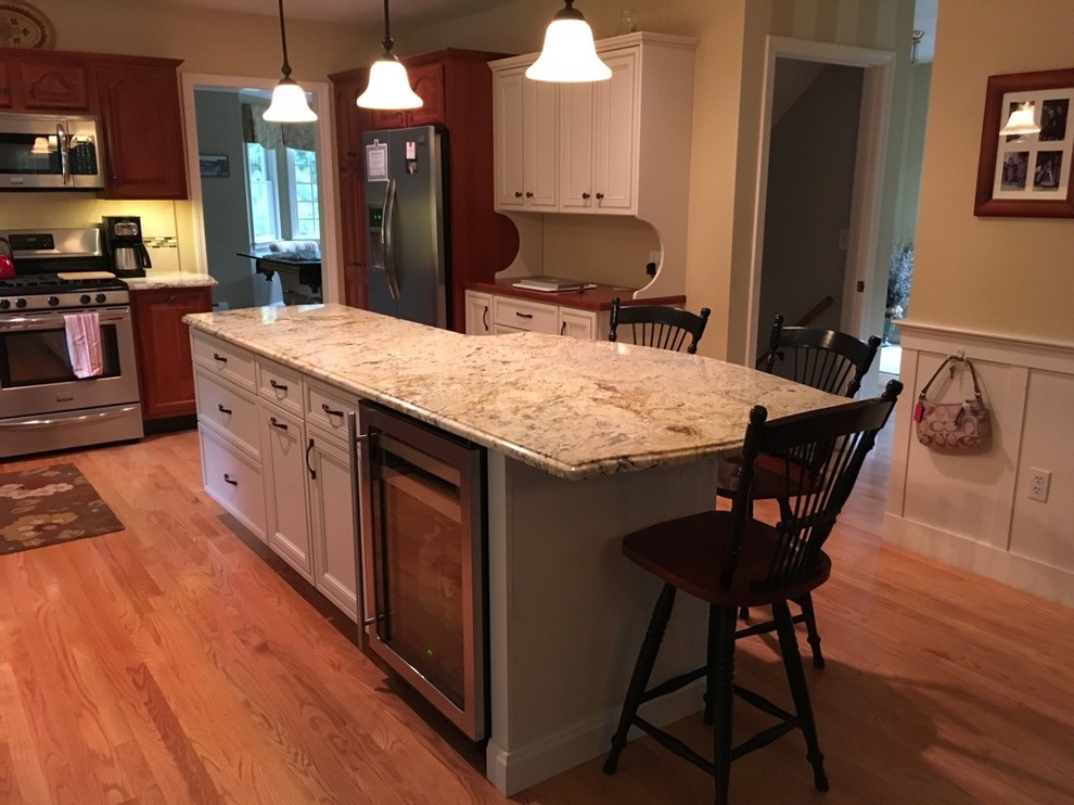 Example of a transitional u-shaped light wood floor eat-in kitchen design in Boston with an undermount sink, raised-panel cabinets, granite countertops, subway tile backsplash, stainless steel appliances and an island