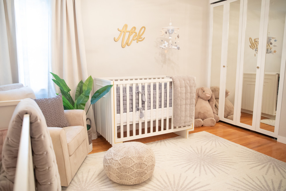 This is an example of a mid-sized modern gender-neutral nursery in Los Angeles with grey walls, laminate floors and brown floor.