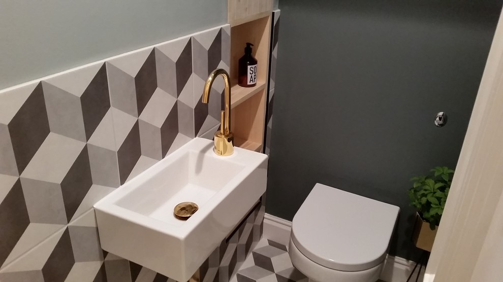 Small contemporary powder room in London with recessed-panel cabinets, light wood cabinets, multi-coloured tile and a wall-mount sink.