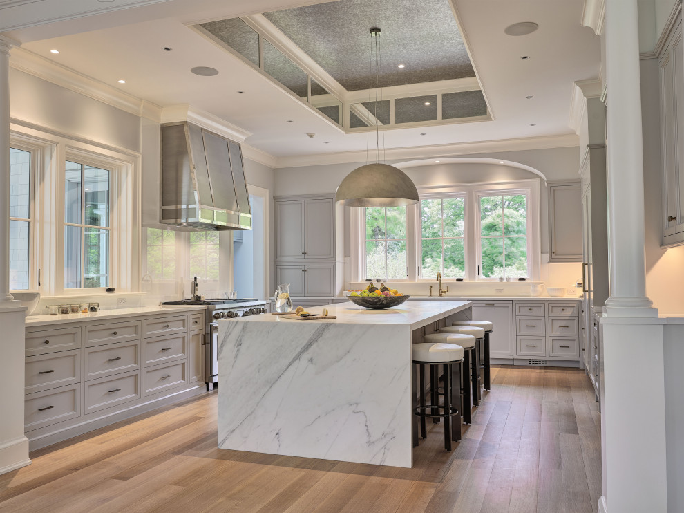 Inspiration for an expansive transitional u-shaped kitchen in New York with an undermount sink, recessed-panel cabinets, grey cabinets, with island, beige floor and grey benchtop.