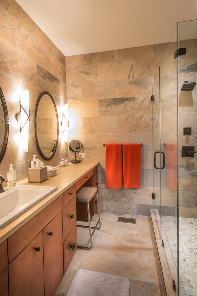 Example of a mid-sized transitional 3/4 beige tile, gray tile and stone tile porcelain tile corner shower design with flat-panel cabinets, medium tone wood cabinets, beige walls, a drop-in sink and quartzite countertops