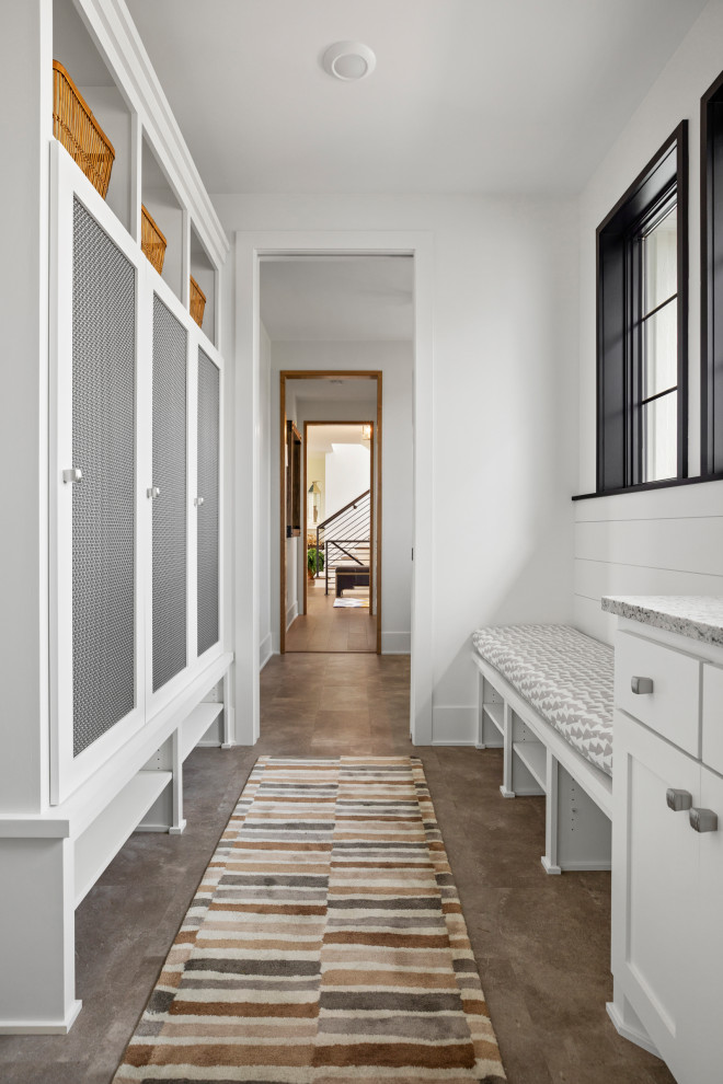 Cette photo montre une grande entrée tendance avec un vestiaire, un mur blanc, un sol en vinyl et un sol marron.