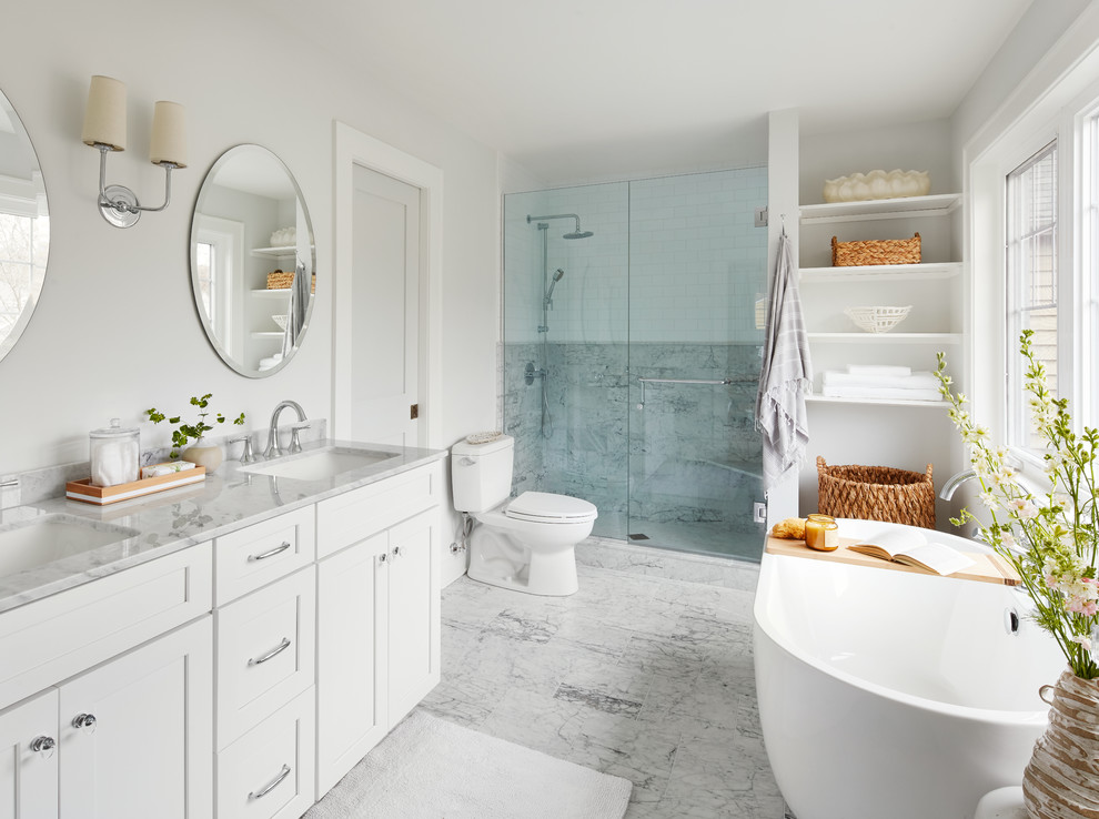 Inspiration for a mid-sized transitional master gray tile, white tile and marble tile marble floor and gray floor freestanding bathtub remodel in Chicago with shaker cabinets, white cabinets, a two-piece toilet, gray walls, an undermount sink, marble countertops, a hinged shower door and white countertops